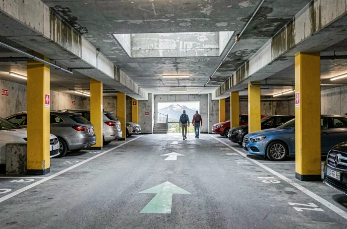 Parking souterrain à étages dans une ville alpine française près de Chamonix avec signalisation et promeneurs en tenue de randonnée